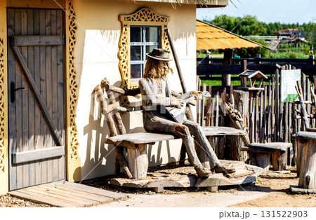 A museum exhibit depicts a village man playing the balalaika while sitting on a bench in a village with a village hut in the background, country 131522903