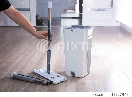 Washing and cleaning the room with a modern mop with a bucket and wringer. Modern novelty for cleaning. Copy space for text, automatic spin Washing and cleaning the room with a modern mop with a bucket and wringer. Modern novelty for cleaning. Copy space for text, automatic spin 131522948