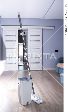 Modern mop with wringing bucket in room against room interior background. Apartment cleaning, close-up Modern mop with wringing bucket in room against room interior background. Apartment cleaning, close-up 131522949