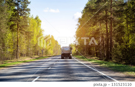Tanker truck transports milk along country road against forest and sun in summer. Copy space for text, agriculture Tanker truck transports milk along country road against forest and sun in summer. Copy space for text, agriculture 131523110