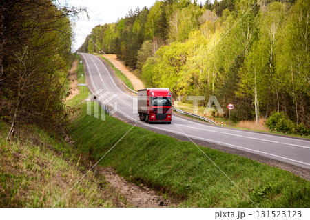 Red truck with tarpaulin semitrailer transports cargo on country road. Concept of forwarding driver, cargo transportation and business, industry Red truck with tarpaulin semitrailer transports cargo on country road. Concept of forwarding driver, cargo transportation and business, industry 131523123