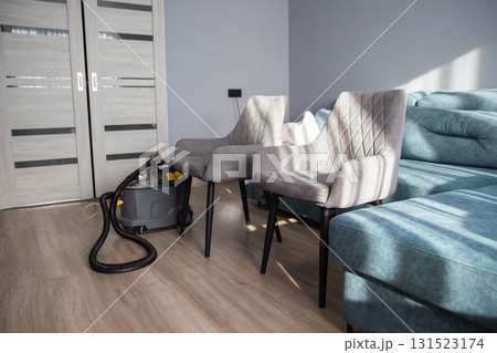 Cleaning equipment ready near grey chairs in a modern living room with sunlight streaming through the window Cleaning equipment ready near grey chairs in a modern living room with sunlight streaming through the window 131523174