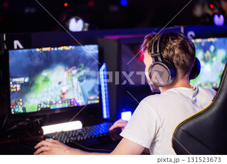 Young gamer participating in an esports tournament in a dimly lit arena while playing an online multiplayer game Young gamer participating in an esports tournament in a dimly lit arena while playing an online multiplayer game 131523673