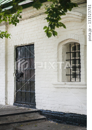 Old brick building with a black door and barred window in a quiet neighborhood Old brick building with a black door and barred window in a quiet neighborhood 131523781