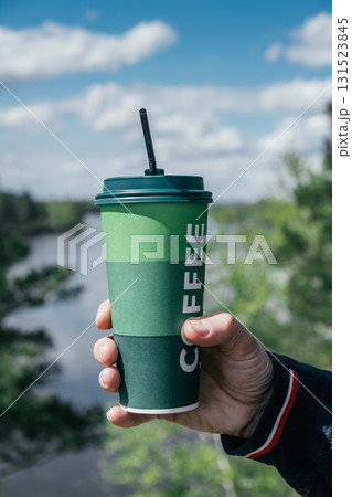 enjoying refreshing coffee cup by river on sunny day. vertical. closeup. 131523845