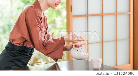 温泉旅館の客室でお茶を淹れる旅館スタッフ・仲居さんの女性 温泉旅館の客室でお茶を淹れる旅館スタッフ・仲居さんの女性 131524096