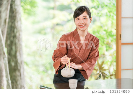 温泉旅館の客室でお茶を淹れる旅館スタッフ・仲居さんの女性 温泉旅館の客室でお茶を淹れる旅館スタッフ・仲居さんの女性 131524099