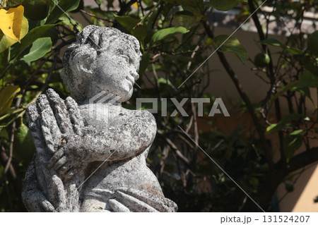 Stone sculpture near house, in park among bushes and trees. Art and design, aesthetics in Europe, Italy. Nature and seasonality.  131524207