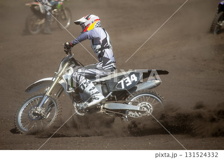 Motocross rider perform turn on dusty track Motocross rider perform turn on dusty track 131524332