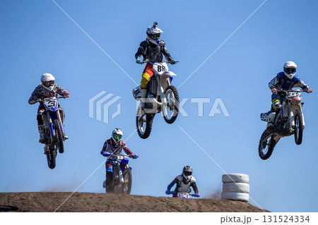 Group motocross riders performing high jump over hill Group motocross riders performing high jump over hill 131524334