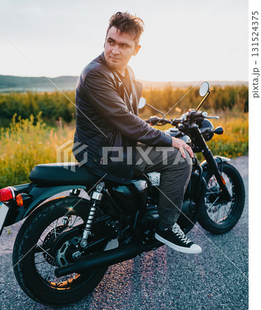 Stylish young man sitting on black vintage motorcycle outdoors Stylish young man sitting on black vintage motorcycle outdoors 131524375