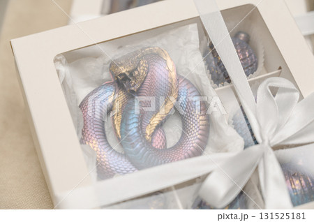 A close-up of a handmade chocolate gift box in the shape of a snake. 131525181