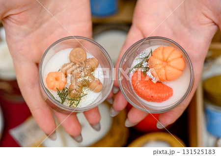 Two Christmas candles with gingerbread and tangerines in glass candlesticks 131525183