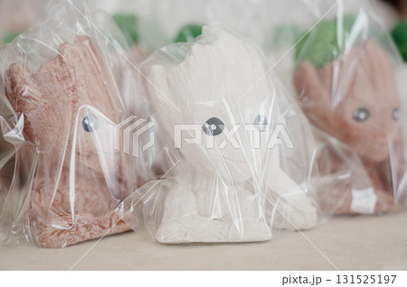 A row of decorative plaster figurines in the form of faces and figures on a table 131525197