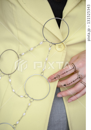 A girl in a yellow jacket shows off an original chain belt with rings and pearls 131525343