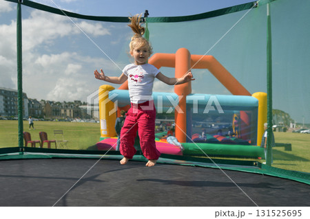 A girl in fuchsia pants jumping on a trampoline A girl in fuchsia pants jumping on a trampoline 131525695