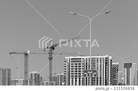 Monochrome view of construction cranes over unfinished highrise tower with steel framework in urban Monochrome view of construction cranes over unfinished highrise tower with steel framework in urban 131526858
