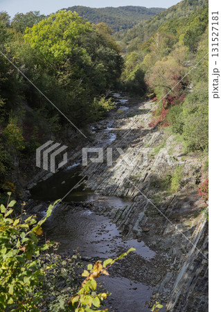 Scenic view of a river valley surrounded by greenery, with rocky terrain and a small wooden structure nestled on the bank Scenic view of a river valley surrounded by greenery, with rocky terrain and a small wooden structure nestled on the bank 131527181