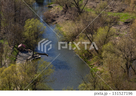 Tranquil river bends through lush greenery in a serene natural setting during early spring Tranquil river bends through lush greenery in a serene natural setting during early spring 131527196