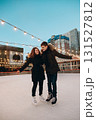 A young couple in love skating on a skating rink, arms apart, look at each other and smile 131527812