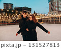 A young couple in love skating on a skating rink, arms apart, look at each other and smile 131527813