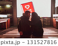 A young couple in love is sitting in a street cinema and looking at each other, hugging and kissing against the background of the screen 131527816