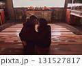 A young couple in love is sitting in a street cinema and looking at each other, hugging and kissing against the background of the screen 131527817
