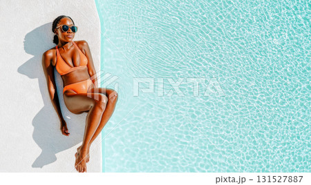 Black young woman relaxing by a swimming pool in swimsuit on sunny day, yop view, copy space 131527887