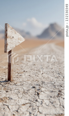 Wooden Arrow Sign On Cracked Desert Ground With Mountains In Background. Symbol Of Direction And Guidance In Barren Landscape 131530349