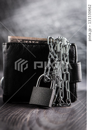 A wallet closed with a chain represents limited access to money A wallet closed with a chain represents limited access to money 131530662