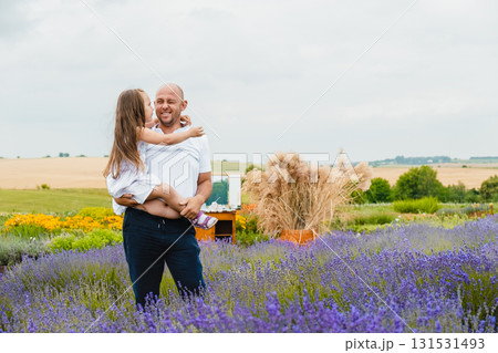 A young father holds his daughter in his arms in a lavender field A young father holds his daughter in his arms in a lavender field 131531493