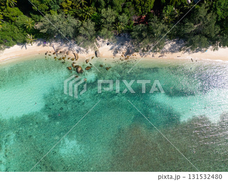 Transparent turquoise water with visible rocks near a sandy shore surrounded by lush greenery. Ko Pha Ngan, Thailand. Transparent turquoise water with visible rocks near a sandy shore surrounded by lush greenery. Ko Pha Ngan, Thailand. 131532480