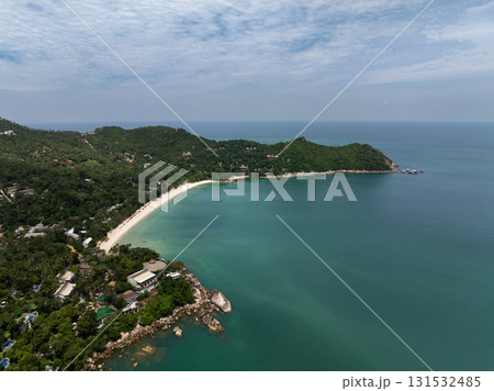 A tropical bay featuring a pristine beach with emerald green waters and vibrant surroundings under a bright sky. Ko Pha Ngan, Thailand. A tropical bay featuring a pristine beach with emerald green waters and vibrant surroundings under a bright sky. Ko Pha Ngan, Thailand. 131532485