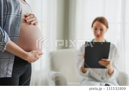 Pregnant woman hands touching big belly in doctor office. Female doctor examining pregnant woman. Gynecologist doctor consulting patient about pregnancy in hospital. Visit to doctor medical checkup 131532809