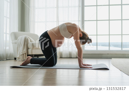 Pregnancy yoga fitness workout training. Pregnant woman practicing yoga at home. Pregnant girl doing sports exercise on yoga mat indoor. Woman with big belly have fitness training practicing asana 131532817