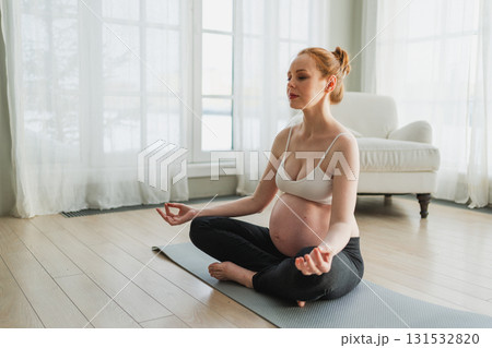 Pregnancy prenatal breathing. Pregnant woman with big belly sitting in lotus pose on yoga matt at home. Pregnant girl practicing yoga mindfulness meditation. Relaxation self care during pregnancy Pregnancy prenatal breathing. Pregnant woman with big belly sitting in lotus pose on yoga matt at home. Pregnant girl practicing yoga mindfulness meditation. Relaxation self care during pregnancy 131532820