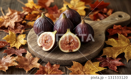 Fresh figs, whole and sliced, on rustic wooden cutting board, surrounded by colorful autumn leaves. Seasonal fruit still life. Organic natural healthy food rich in vitamins. Fall harvest decoration. Fresh figs, whole and sliced, on rustic wooden cutting board, surrounded by colorful autumn leaves. Seasonal fruit still life. Organic natural healthy food rich in vitamins. Fall harvest decoration. 131533120