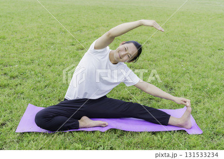 公園の芝生の上でヨガをする若い男性 131533234