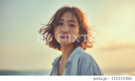 夕暮れの海辺にたたずむ女性の切なさと静けさを感じるポートレート 131533360
