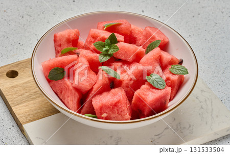 Ripe watermelon slices with mint leaves in a white round plate on the table Ripe watermelon slices with mint leaves in a white round plate on the table 131533504