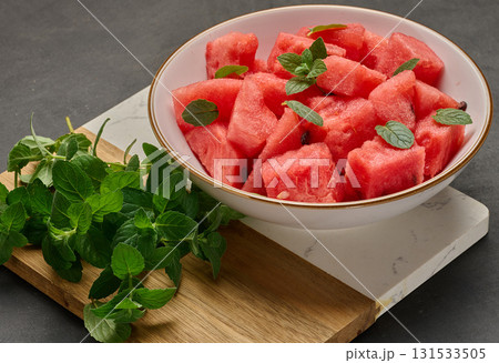 Plate full of diced watermelon garnished with fresh mint. Top view. Plate full of diced watermelon garnished with fresh mint. Top view. 131533505