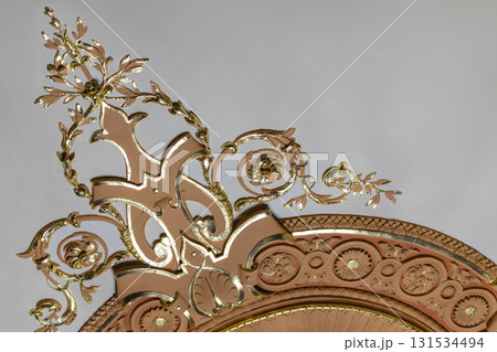 A decorative gold and pink ornamental piece featuring scrolling vines and leaves 131534494