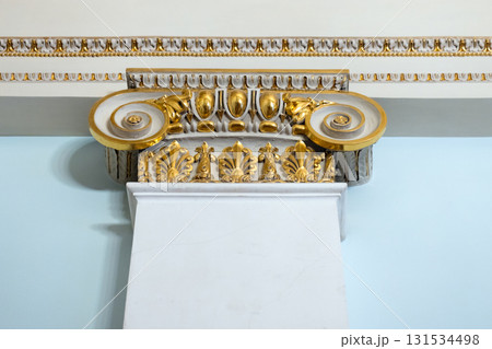 A richly decorated architectural capital featuring gold leaf and scrollwork A richly decorated architectural capital featuring gold leaf and scrollwork 131534498