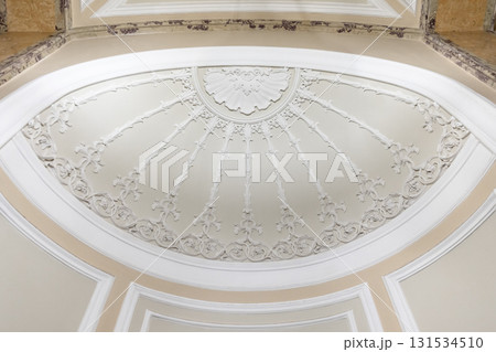 A grand, decorative ceiling dome featuring radial floral plasterwork 131534510