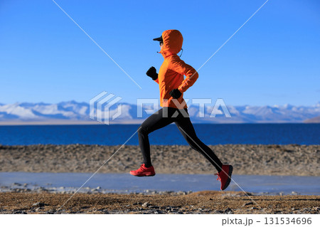 Woman runner training at winter lakeside Woman runner training at winter lakeside 131534696