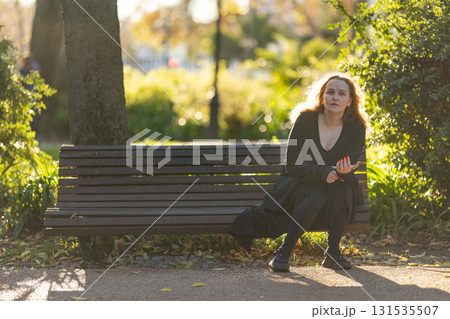 Woman experiencing contemplation while sitting on park bench 131535507