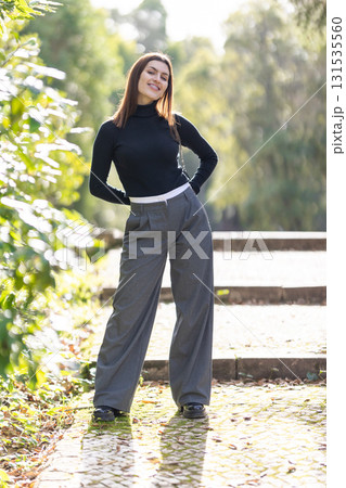 Young woman smiling, standing in fashion wide-leg pants Young woman smiling, standing in fashion wide-leg pants 131535560