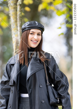 Young woman smiling while wearing black beret and stylish trench coat 131535600