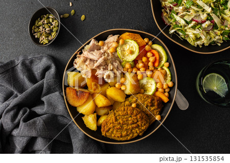 Enjoy a delicious and nutritious breakfast featuring baked sweet potato, colorful vegetables, lentil cutlets, chicken, and a fresh salad 131535854