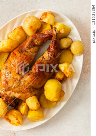 A beautifully presented dish features a whole baked rabbit surrounded by tender, golden-roasted potatoes. This comforting meal is perfect for family gatherings or special occasions. 131535864